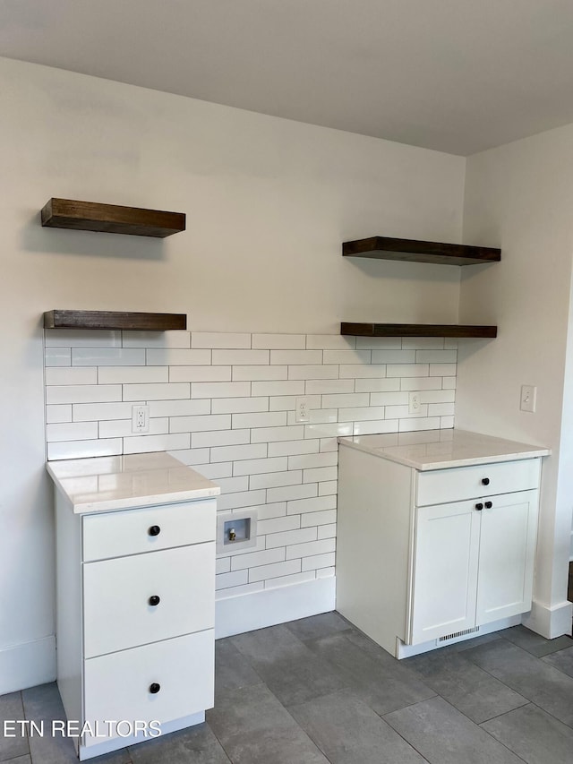 interior space featuring tasteful backsplash, white cabinets, open shelves, light countertops, and dark tile patterned floors