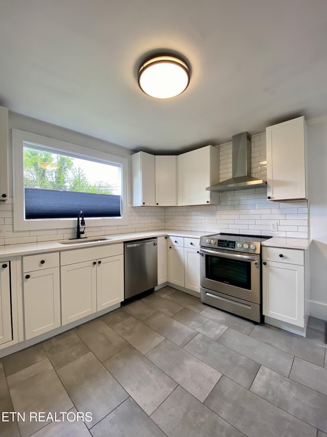 kitchen featuring a sink, decorative backsplash, appliances with stainless steel finishes, and wall chimney exhaust hood