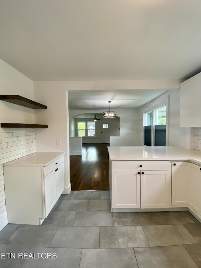kitchen with white cabinetry, light countertops, open shelves, and a peninsula