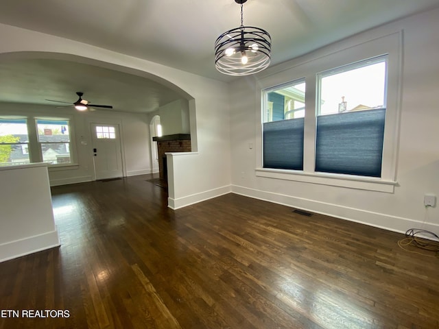 interior space featuring dark wood-style flooring, visible vents, baseboards, and arched walkways
