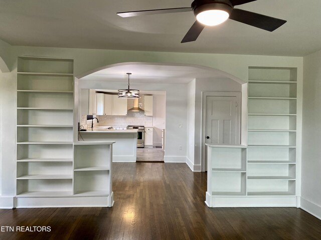 interior space featuring dark wood-type flooring, ceiling fan, arched walkways, and baseboards