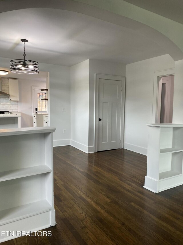 interior space with arched walkways, baseboards, and dark wood-style floors
