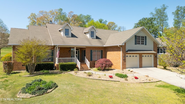 new england style home featuring concrete driveway, a front lawn, an attached garage, brick siding, and a porch