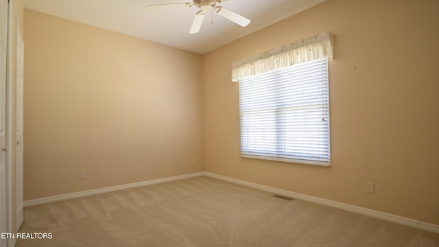 unfurnished room with baseboards, light colored carpet, ceiling fan, and visible vents
