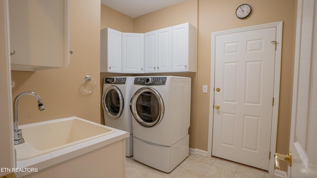 washroom with light tile patterned floors, a sink, cabinet space, and washer and clothes dryer
