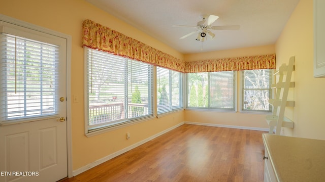 unfurnished sunroom with a wealth of natural light, wood finished floors, and baseboards