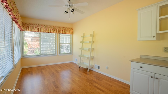 unfurnished dining area with light wood-style flooring, baseboards, and ceiling fan