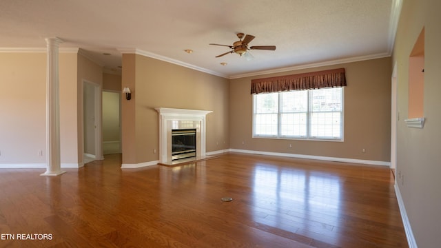 unfurnished living room with ornate columns, wood finished floors, ceiling fan, and crown molding