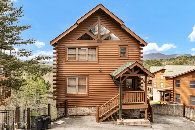 view of front of house featuring a mountain view, fence, and log exterior
