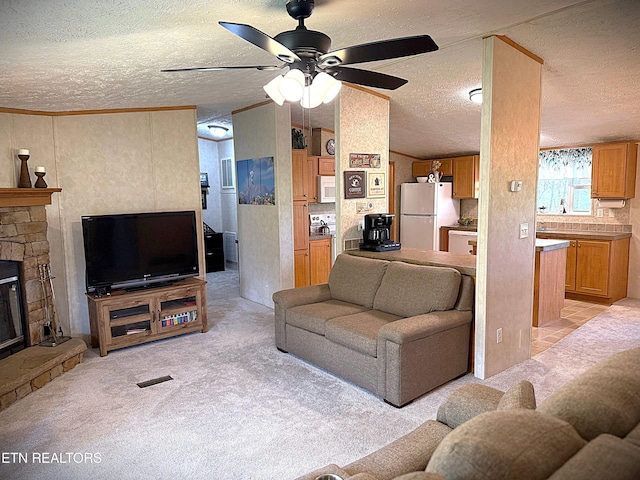 living area with a textured ceiling, light colored carpet, a ceiling fan, and a stone fireplace