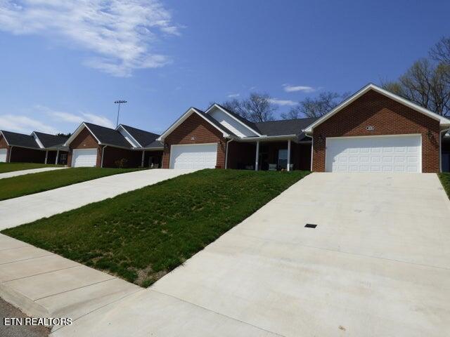 single story home with a front yard, brick siding, a garage, and driveway