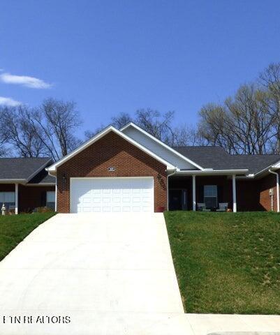 ranch-style house with brick siding, driveway, an attached garage, and a front lawn