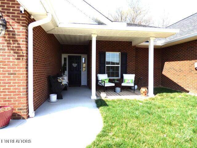 doorway to property featuring brick siding and covered porch