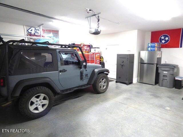 garage featuring freestanding refrigerator and a garage door opener