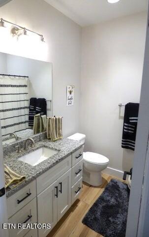 full bathroom featuring vanity, a shower with curtain, toilet, wood finished floors, and baseboards