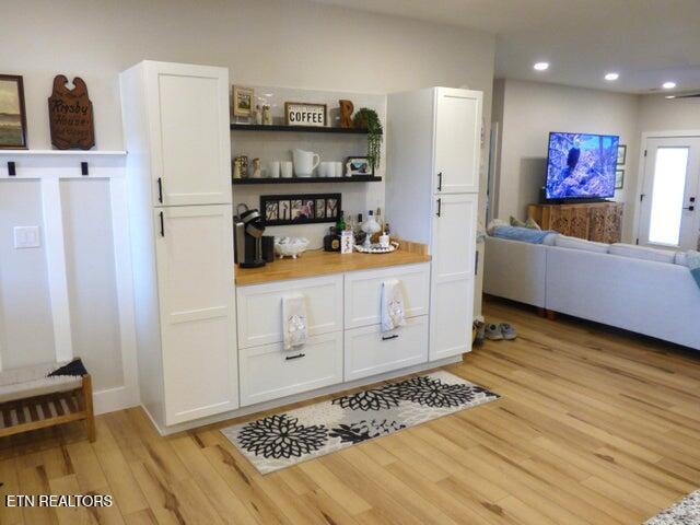 kitchen featuring open floor plan, open shelves, light wood finished floors, and white cabinetry