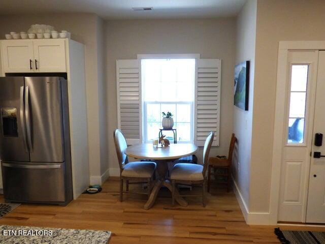 dining space with visible vents, light wood-type flooring, baseboards, and a healthy amount of sunlight