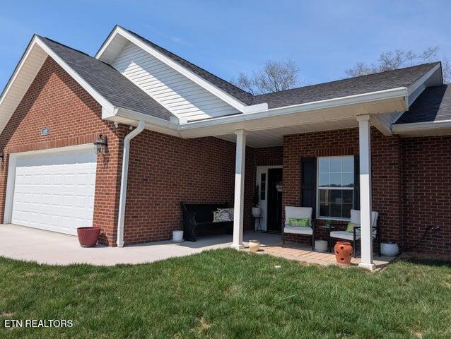 exterior space with brick siding, a front lawn, and a garage