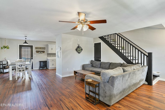 living room with baseboards, a ceiling fan, stairway, and dark wood-style floors