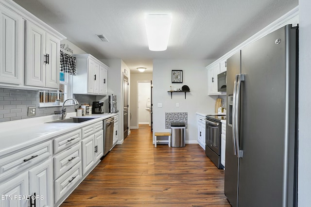 kitchen featuring dark wood-type flooring, tasteful backsplash, white cabinetry, appliances with stainless steel finishes, and a sink
