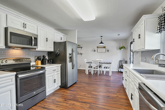 kitchen featuring a sink, light countertops, appliances with stainless steel finishes, dark wood-style floors, and white cabinetry