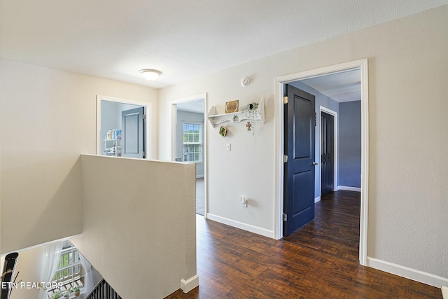 hall with dark wood-style flooring and baseboards