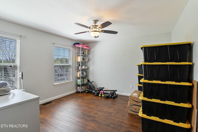 interior space with wood finished floors, baseboards, a ceiling fan, and visible vents