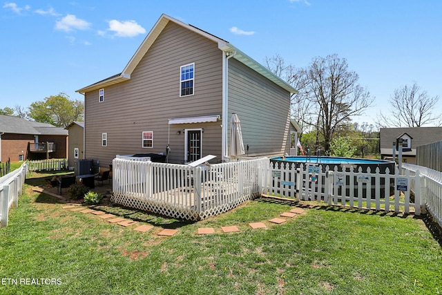 rear view of property with an outdoor pool, a fenced backyard, a wooden deck, and a lawn
