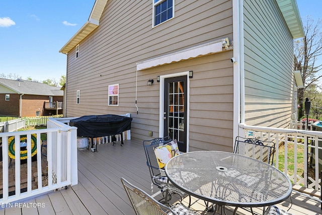 wooden terrace featuring outdoor dining space, grilling area, and fence