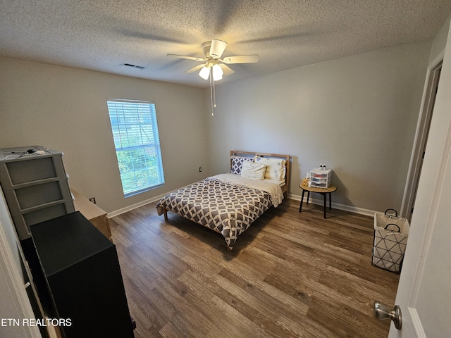 bedroom with visible vents, baseboards, wood finished floors, and a textured ceiling