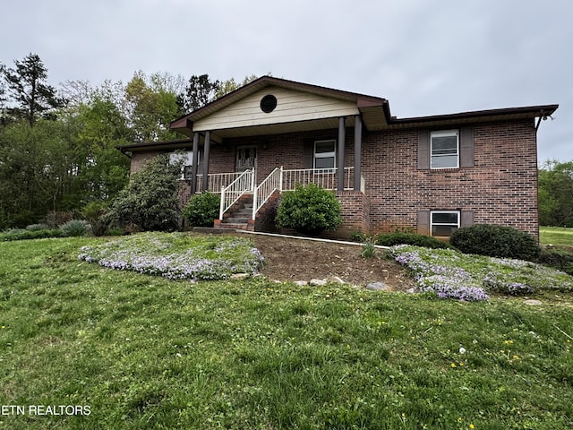single story home with a front yard, brick siding, and covered porch