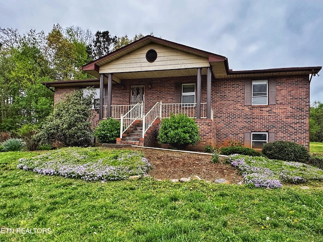 ranch-style home featuring a front yard, brick siding, and covered porch