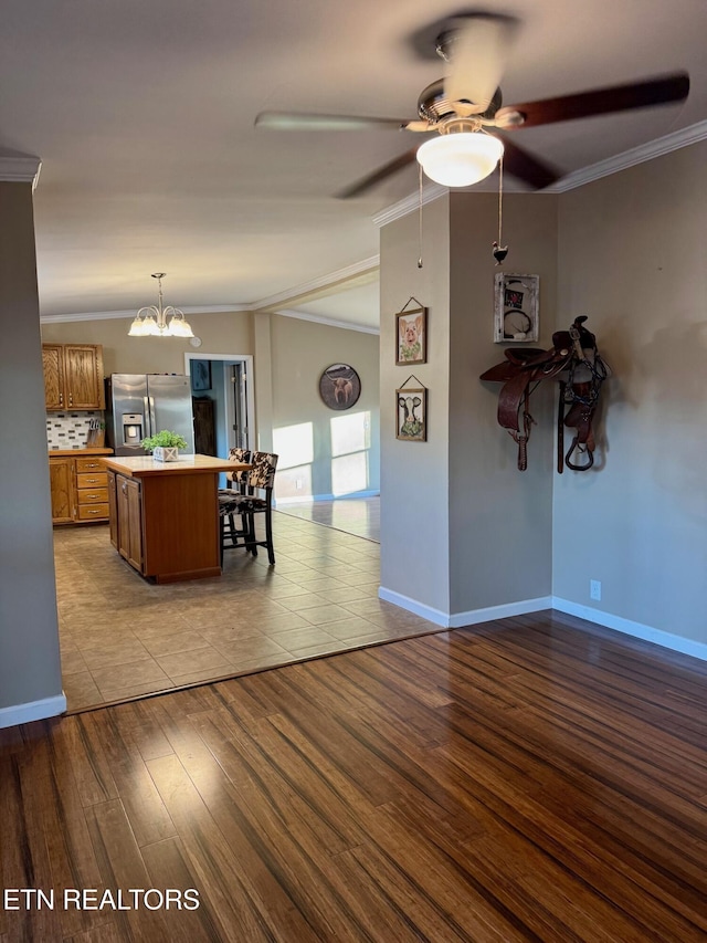 living room featuring ceiling fan with notable chandelier, vaulted ceiling, wood finished floors, and ornamental molding