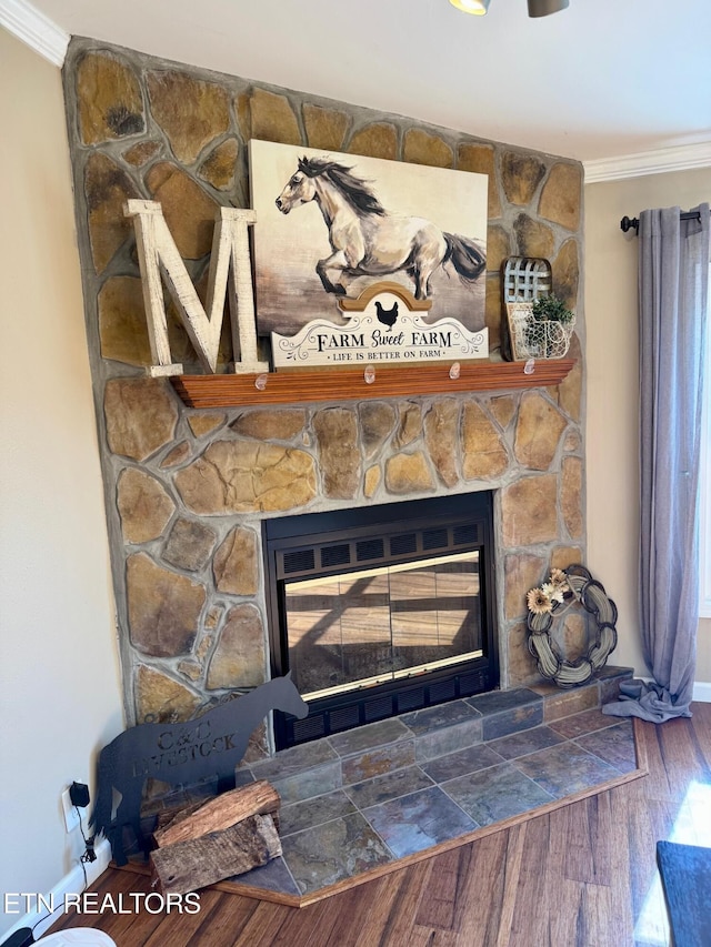 interior details with a stone fireplace, wood finished floors, baseboards, and ornamental molding