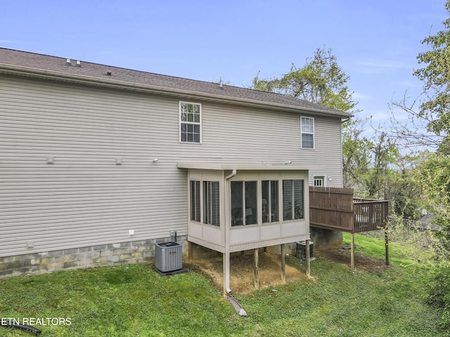 rear view of property with central AC unit, a yard, and a sunroom