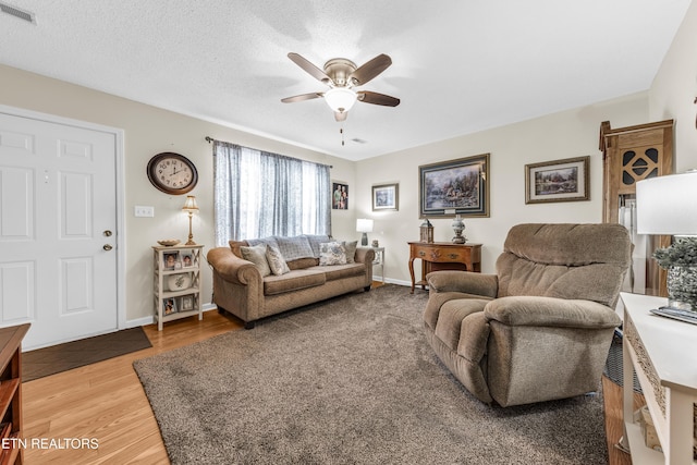 living area with visible vents, baseboards, a ceiling fan, and wood finished floors