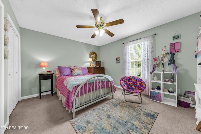 carpeted bedroom with a closet, baseboards, a ceiling fan, and a textured ceiling
