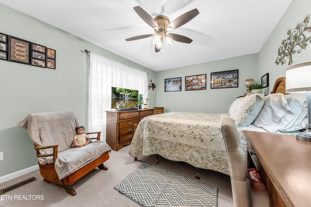 carpeted bedroom featuring visible vents, ceiling fan, baseboards, and a textured ceiling