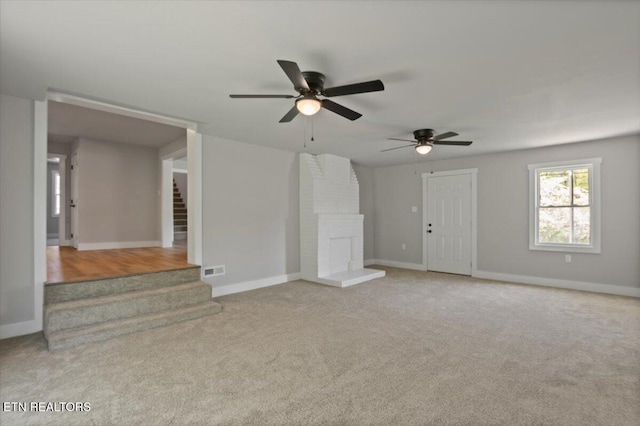 unfurnished living room with ceiling fan, baseboards, visible vents, and stairway