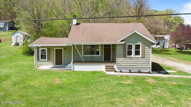 ranch-style house featuring roof with shingles, a front yard, and a porch