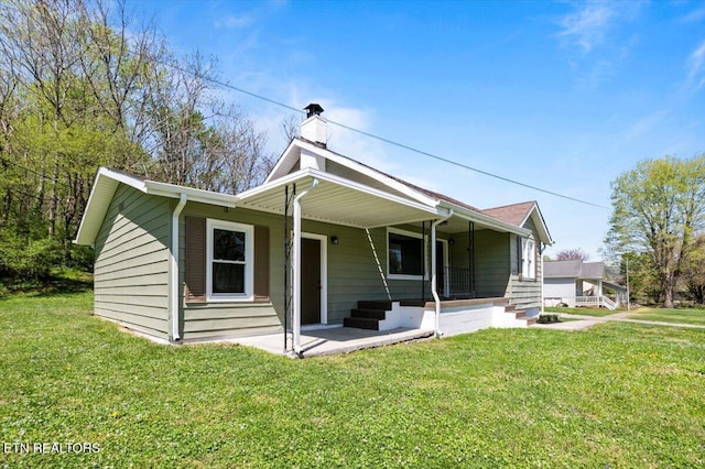 view of front of house featuring a front yard, a porch, and a chimney