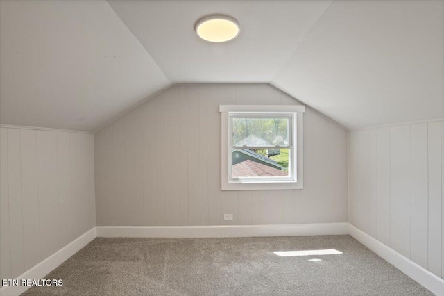 additional living space with carpet flooring, baseboards, and vaulted ceiling