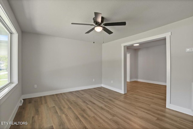 spare room with wood finished floors, ceiling fan, and baseboards