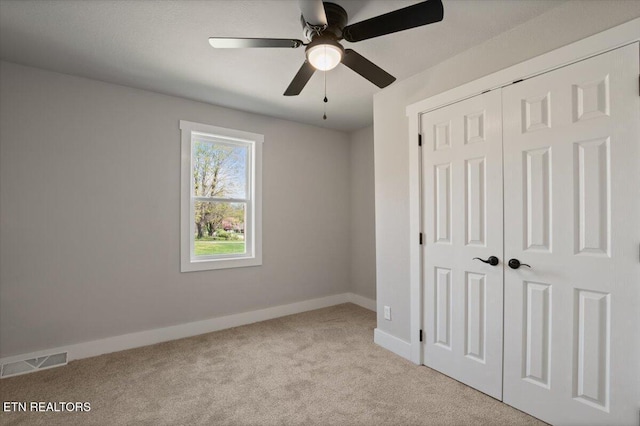 unfurnished bedroom featuring carpet, a closet, a ceiling fan, visible vents, and baseboards