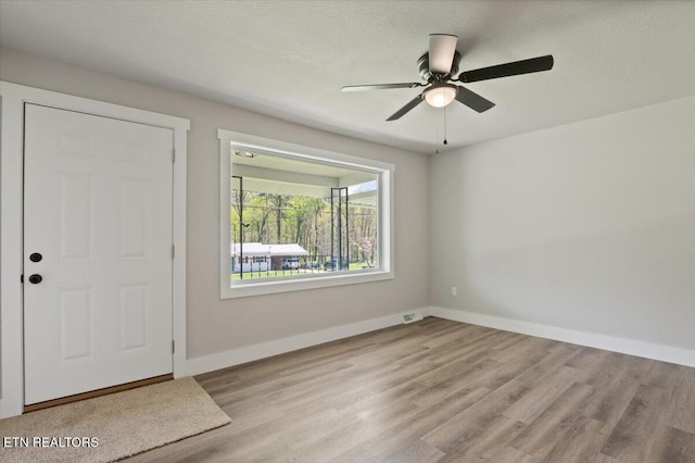 entrance foyer with a textured ceiling, baseboards, a ceiling fan, and wood finished floors
