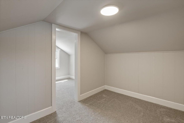 additional living space with carpet floors, baseboards, and vaulted ceiling