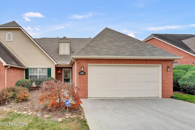 view of front of property with concrete driveway, roof with shingles, stucco siding, brick siding, and a garage