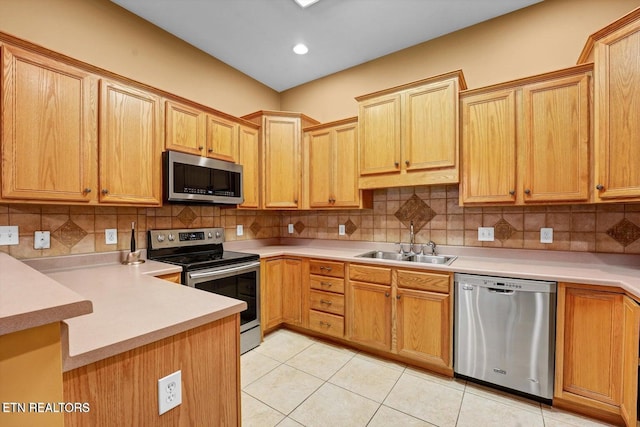 kitchen with light tile patterned floors, tasteful backsplash, appliances with stainless steel finishes, light countertops, and a sink