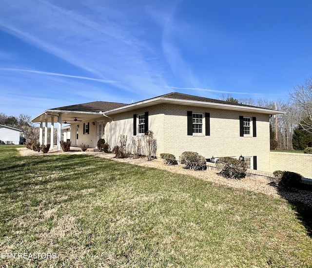 view of property exterior featuring brick siding, a ceiling fan, and a lawn