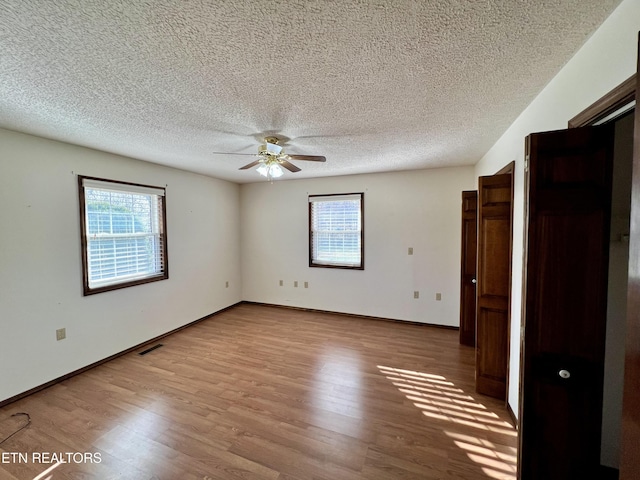 unfurnished bedroom with baseboards, a textured ceiling, visible vents, ceiling fan, and wood finished floors